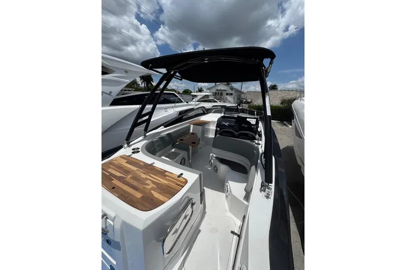 Slide: The Image of 2025 NX Boats NX270 interior with sleek design, wooden accents, and modern features under a cloudy sky. - 16