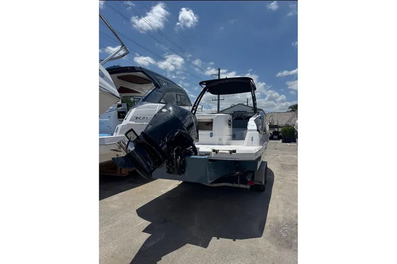 Slide: The Image of 2025 NX Boats NX270 with outboard motor, parked outdoors under a clear blue sky. - 9