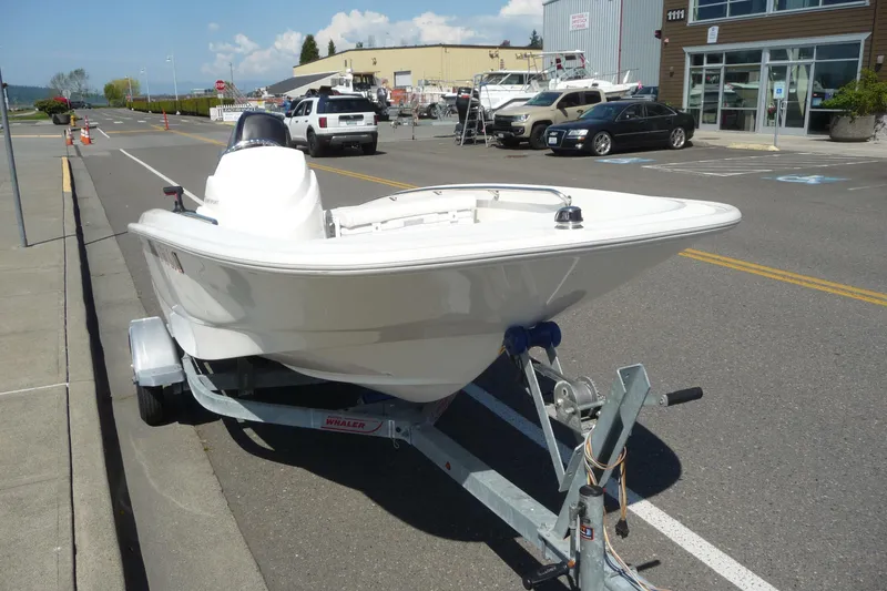 Slide: The Image of 2016 Boston Whaler 130 Super Sport boat on trailer, parked on street. - 10