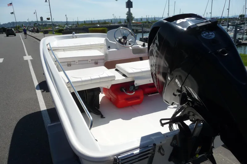 Slide: The Image of 2016 Boston Whaler 130 Super Sport boat with outboard motor, docked near marina. - 4
