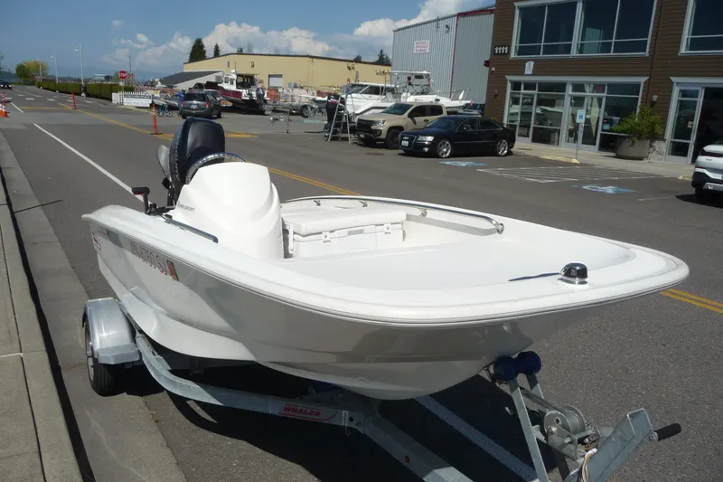 Slide: The Image of 2016 Boston Whaler 130 Super Sport boat on trailer, parked on urban street. - 7