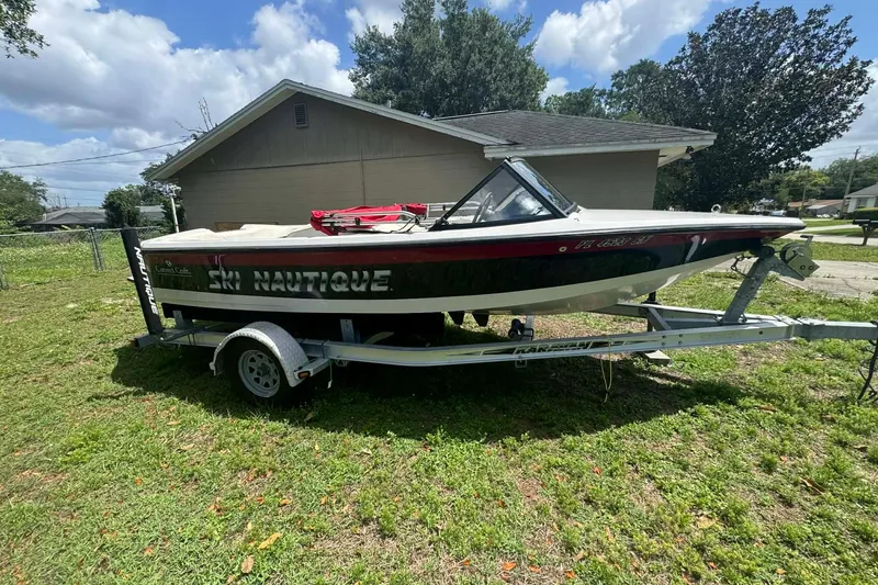 The Image of 1992 Nautique Ski Nautique 200 Closed Bow boat on trailer, parked in grassy yard. - 0