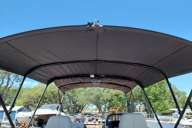 Slide: The Image of 2026 Starcraft RX 23 Q DH boat with canopy, docked under clear blue sky. - 32