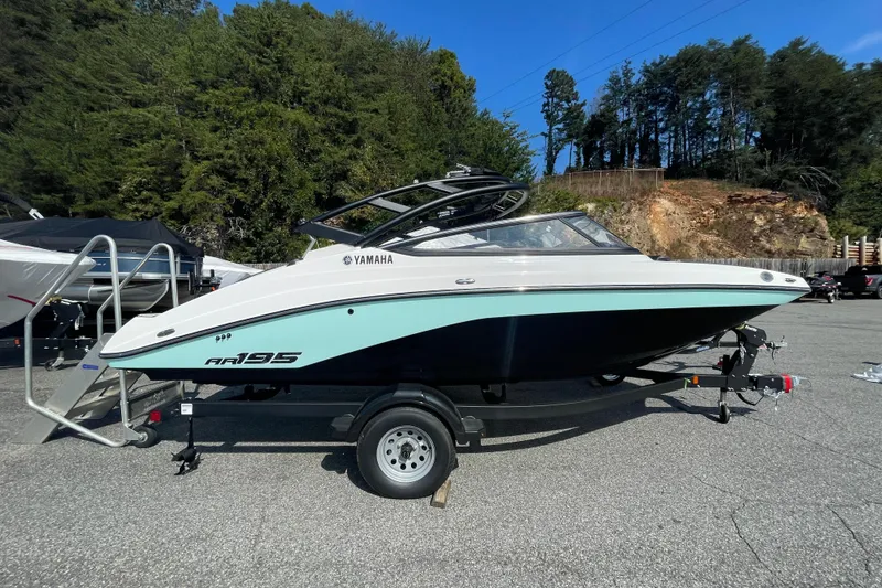 The Image of 2026 Yamaha Boats AR195 on trailer, parked outdoors with forested background. - 0