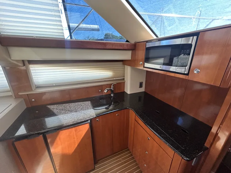 Slide: The Image of The 2007 Meridian 368 Motoryacht's galley features a sleek countertop, wooden cabinets, and a built-in microwave. - 28