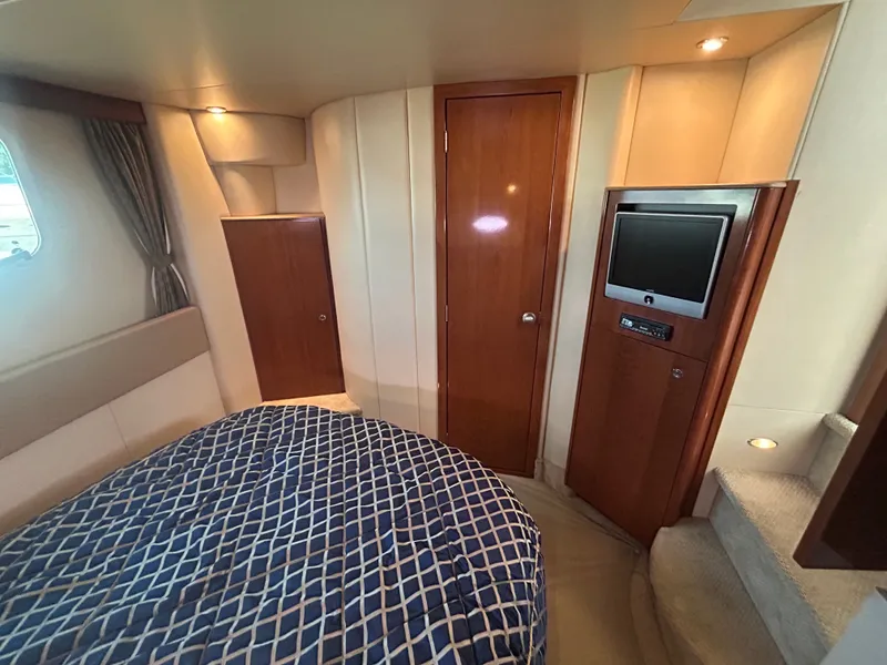 Slide: The Image of The cabin of a 2007 Meridian 368 Motoryacht with a bed, TV, and wooden furnishings. - 26