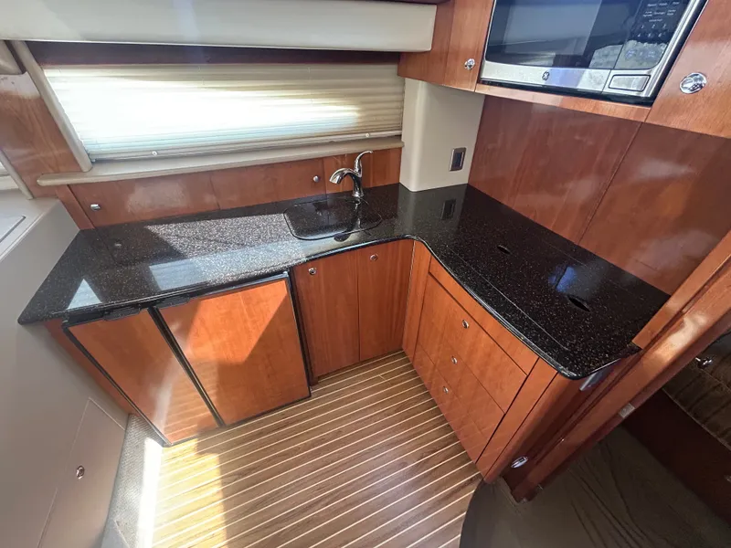 Slide: The Image of The 2007 Meridian 368 Motoryacht's galley features a sleek countertop, wooden cabinets, and a built-in microwave. - 27