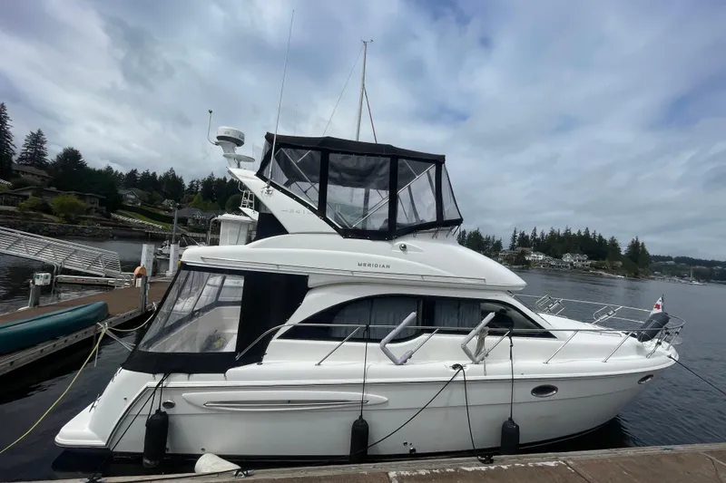 Slide: The Image of 2004 Meridian 341 Sedan yacht docked by a scenic waterfront under cloudy skies. - 36