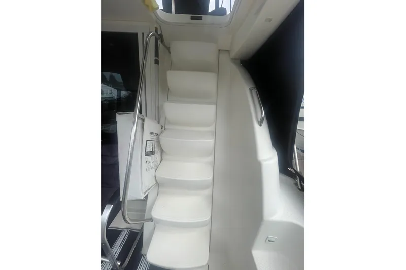 Slide: The Image of Staircase inside 2004 Meridian 341 Sedan yacht, featuring sleek white design and metal handrails. - 6