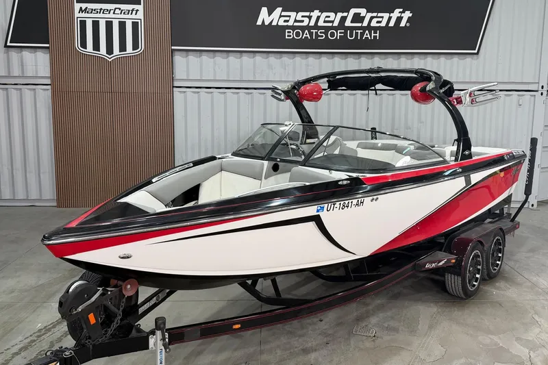 The Image of A 2013 Tigé Z3 boat in a showroom, featuring a striking red and white design on a trailer. - 1