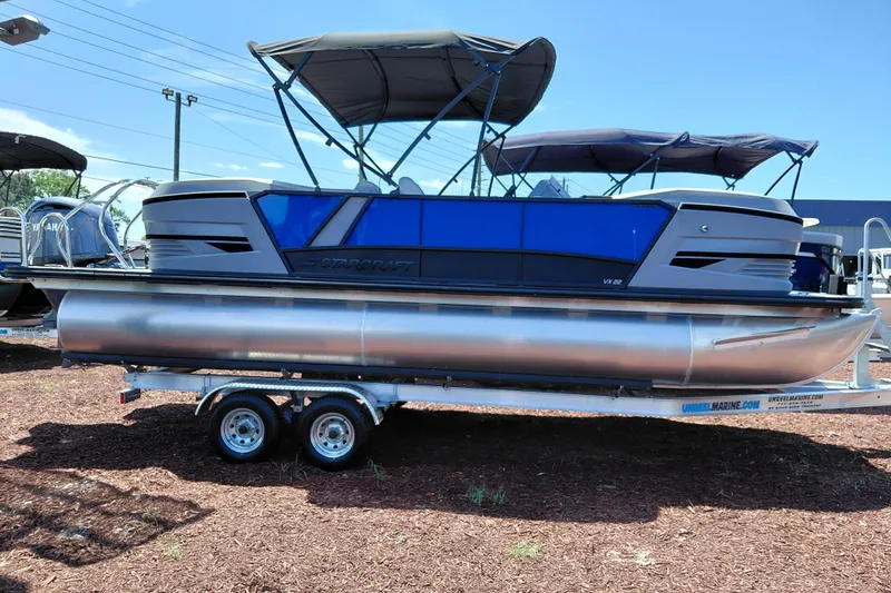 Slide: The Image of 2026 Starcraft VX 22 R DH pontoon boat on trailer, featuring sleek blue design and canopy. - 2