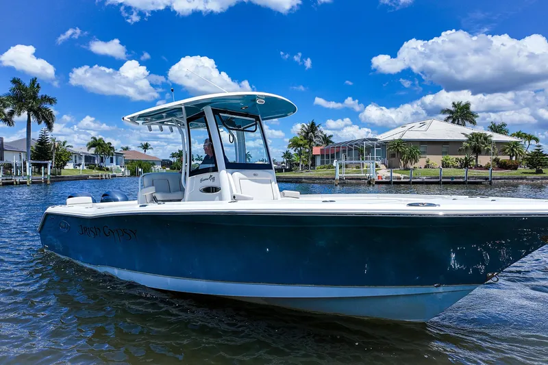 The Image of 2022 Sea Hunt Gamefish 27 boat on a sunny day, docked near waterfront homes. - 0