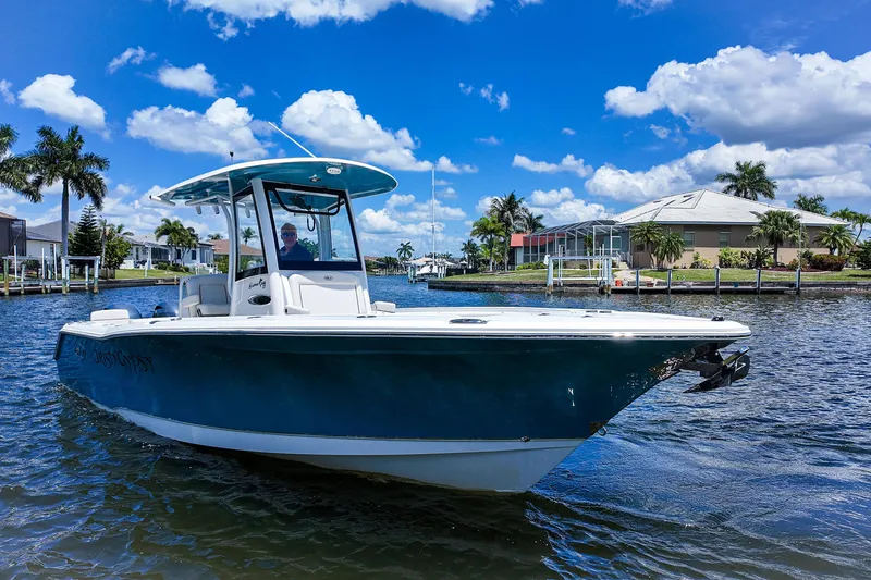 Slide: The Image of 2022 Sea Hunt Gamefish 27 boat cruising on a sunny day with palm trees and houses in the background. - 1