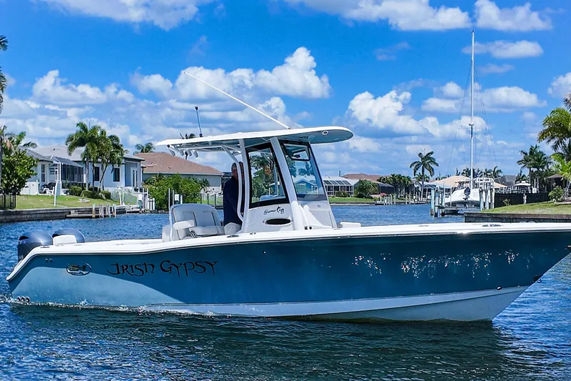 Slide: The Image of 2022 Sea Hunt Gamefish 27 boat cruising on a sunny day in a residential canal. - 2