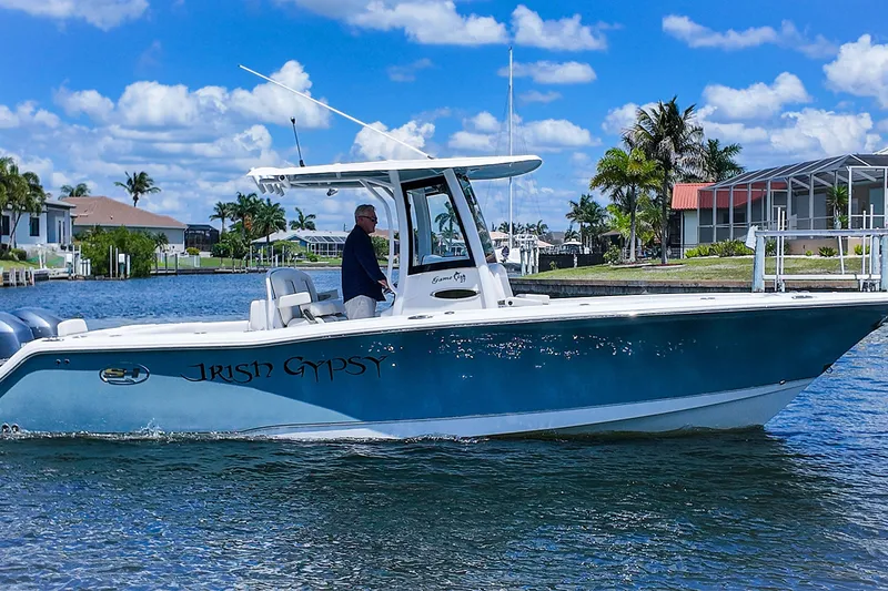 Slide: The Image of 2022 Sea Hunt Gamefish 27 boat on water, clear sky, residential backdrop. - 4