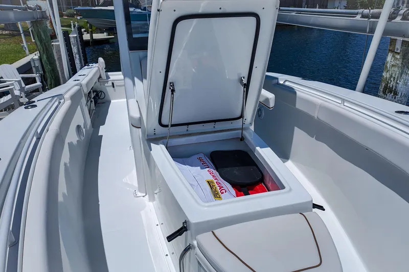 Slide: The Image of 2022 Sea Hunt Gamefish 27 boat with open storage compartment, docked by the water. - 13