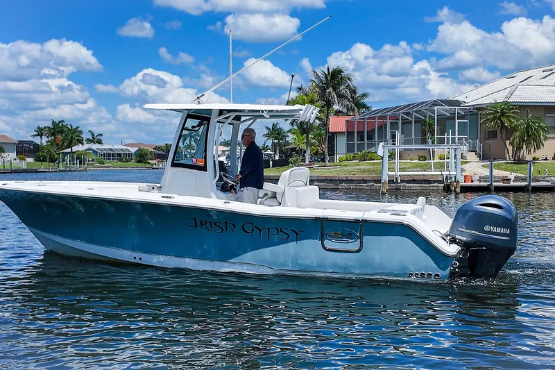 Slide: The Image of 2022 Sea Hunt Gamefish 27 boat on water, clear sky, residential backdrop. - 8