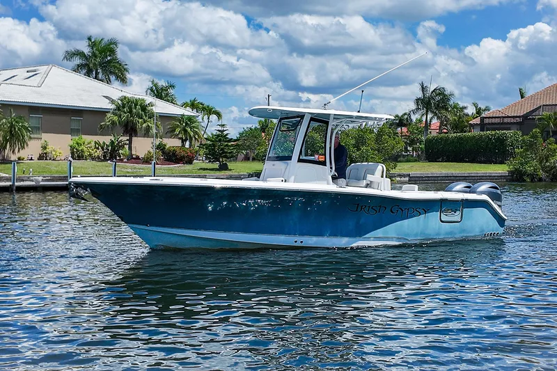 Slide: The Image of 2022 Sea Hunt Gamefish 27 boat on water, surrounded by tropical scenery and houses. - 9