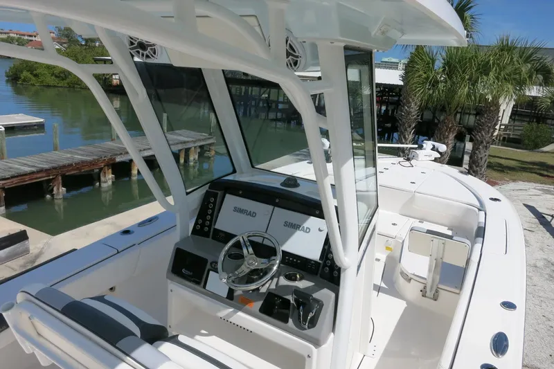 Slide: The Image of 2022 Robalo 266 Cayman boat interior with steering console, dockside view, and palm trees. - 19