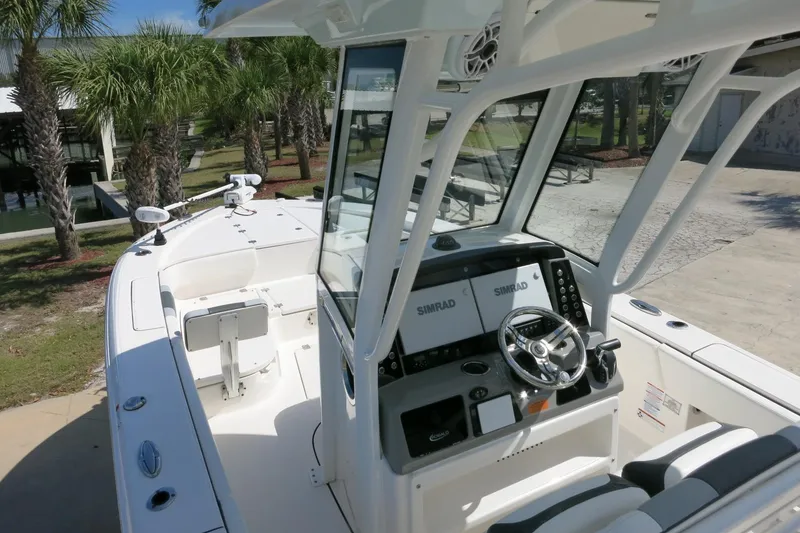 Slide: The Image of 2022 Robalo 266 Cayman boat interior with steering console and seating, surrounded by palm trees. - 20