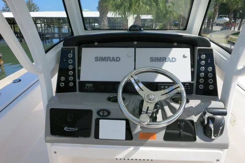 Slide: The Image of 2022 Robalo 266 Cayman boat dashboard with dual Simrad displays and steering wheel. - 22