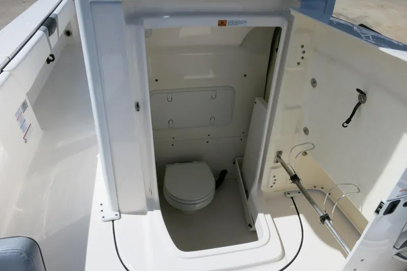 Slide: The Image of 2022 Robalo 266 Cayman boat interior with compact marine toilet and storage area. - 25