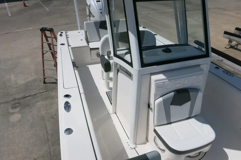 Slide: The Image of 2022 Robalo 266 Cayman boat interior with seating and console, docked on concrete surface. - 30