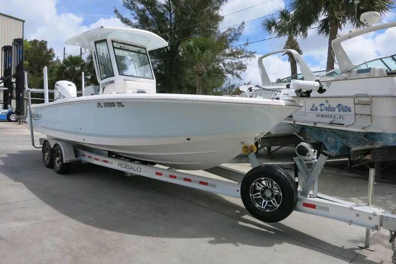 Slide: The Image of 2022 Robalo 266 Cayman boat on trailer, parked outdoors under a clear sky. - 4