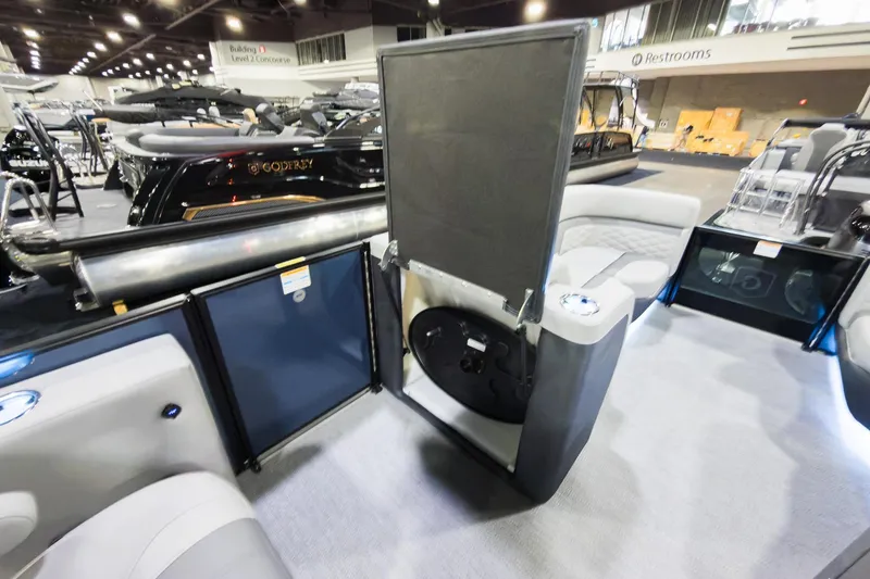 Slide: The Image of 2026 Godfrey Monaco 235 boat interior with flip lounge seating at a showroom. - 19