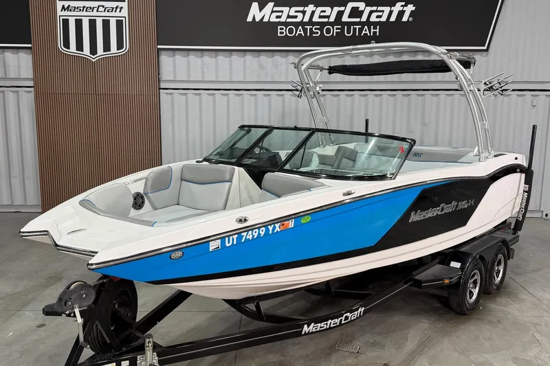 The Image of 2017 MasterCraft NXT22 boat in showroom, blue and white design, on trailer. - 1