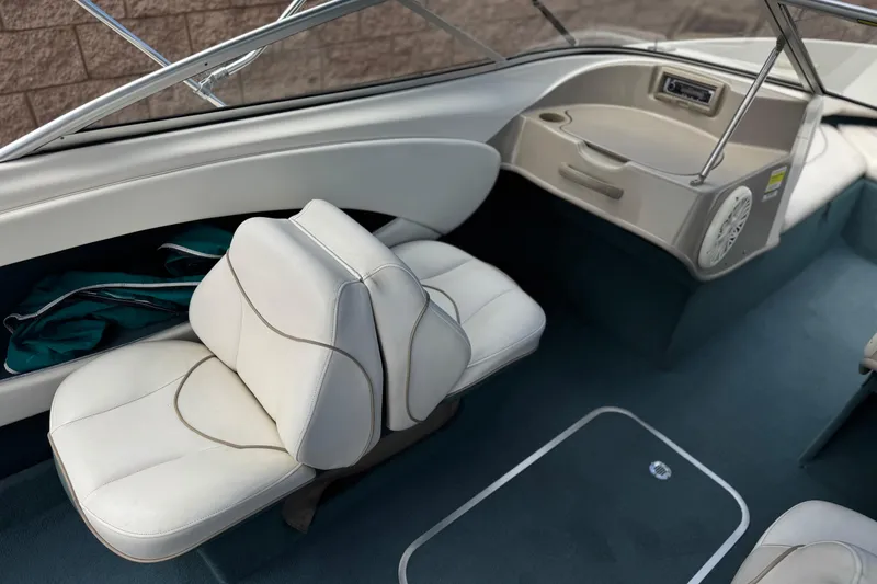 Slide: The Image of Interior of a 2000 Bayliner 2150 Capri boat with white seating and blue carpet. - 15