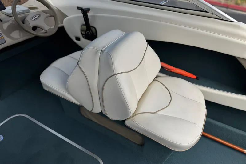 Slide: The Image of Interior of a 2000 Bayliner 2150 Capri boat with white seating and steering wheel. - 19
