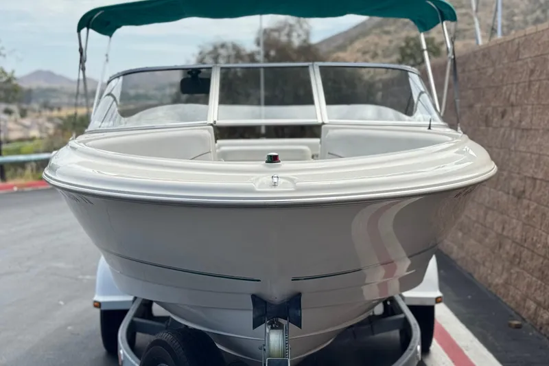 Slide: The Image of 2000 Bayliner 2150 Capri boat on trailer, parked outdoors with scenic background. - 2