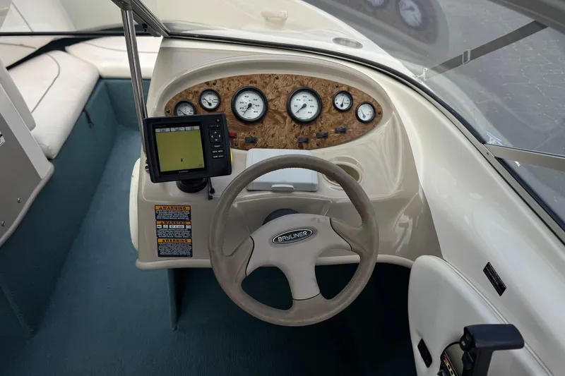 Slide: The Image of 2000 Bayliner 2150 Capri boat dashboard with steering wheel, gauges, and navigation system. - 21
