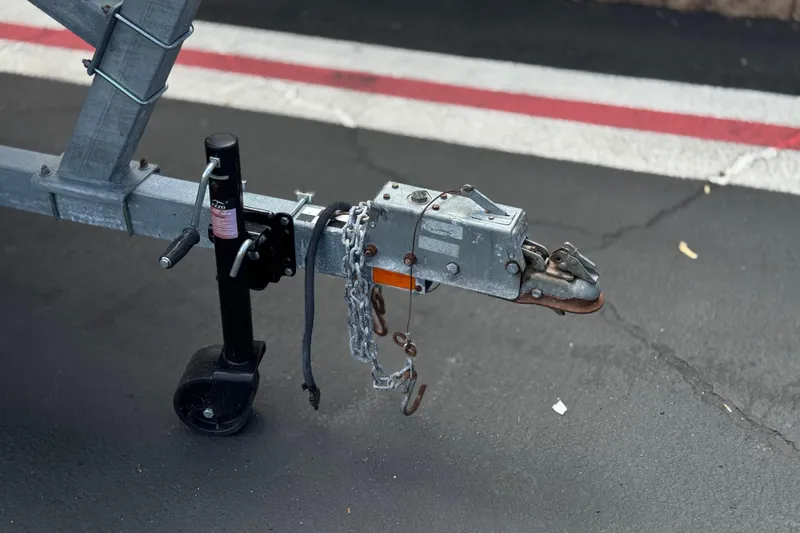 Slide: The Image of Trailer hitch of a 2000 Bayliner 2150 Capri on asphalt, featuring chains and a jack. - 24