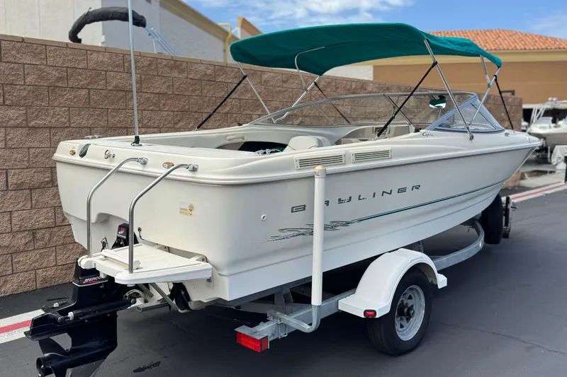 Slide: The Image of 2000 Bayliner 2150 Capri boat with green canopy on trailer, parked outdoors. - 5