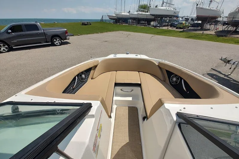 Slide: The Image of 2023 Sea Ray SPX 190 boat interior with tan seating, parked near a lake. - 14