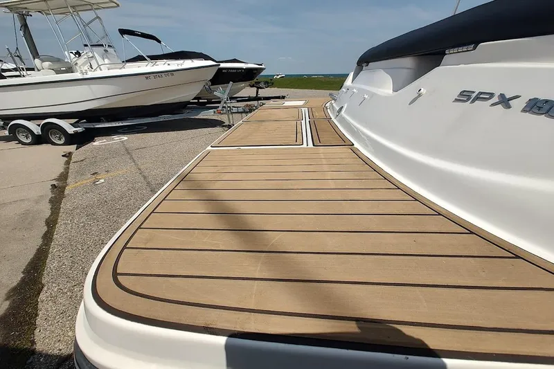 Slide: The Image of 2023 Sea Ray SPX 190 boat with teak deck, parked on a trailer at a marina. - 24