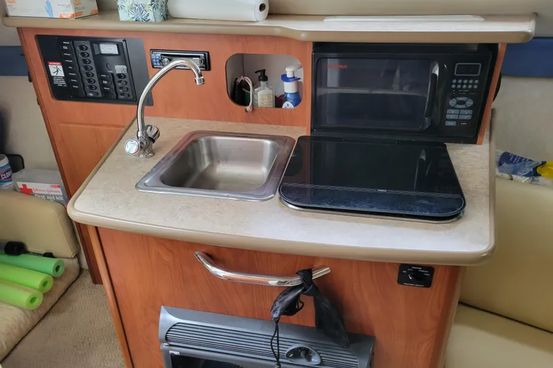 Slide: The Image of 2007 Bayliner 245 Cruiser kitchenette with sink, microwave, and stove. - 24
