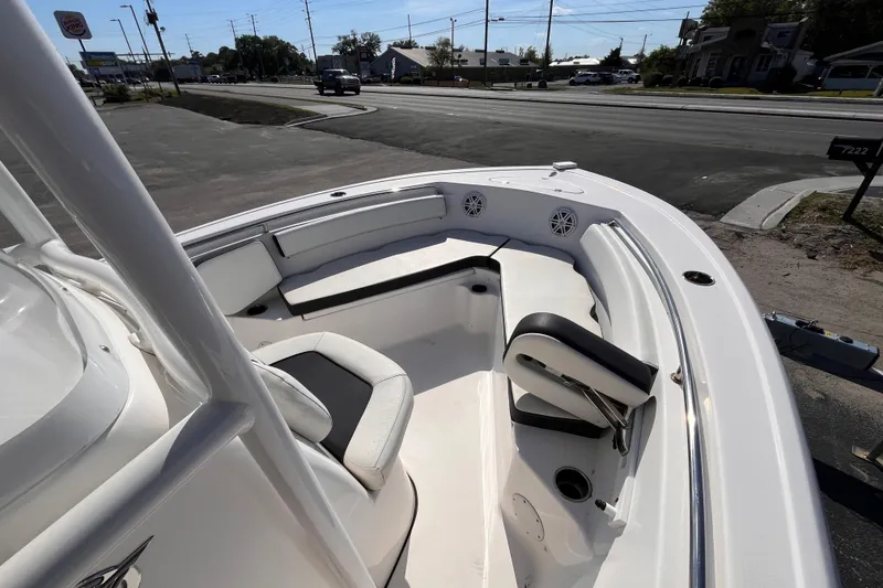 Slide: The Image of 2022 Tidewater 210 LXF boat interior with seating and speakers, parked near a road. - 10