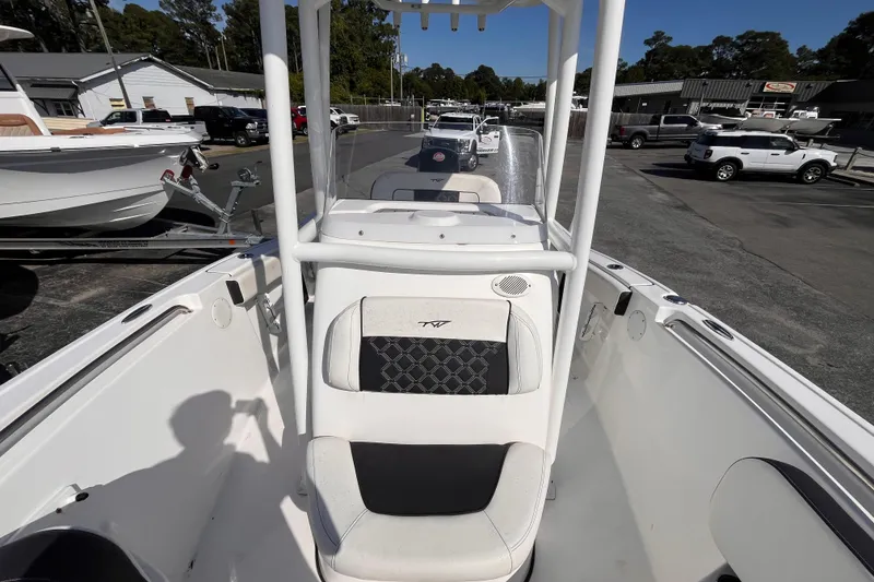 Slide: The Image of 2022 Tidewater 210 LXF boat interior with seating and console, parked in a dealership lot. - 11