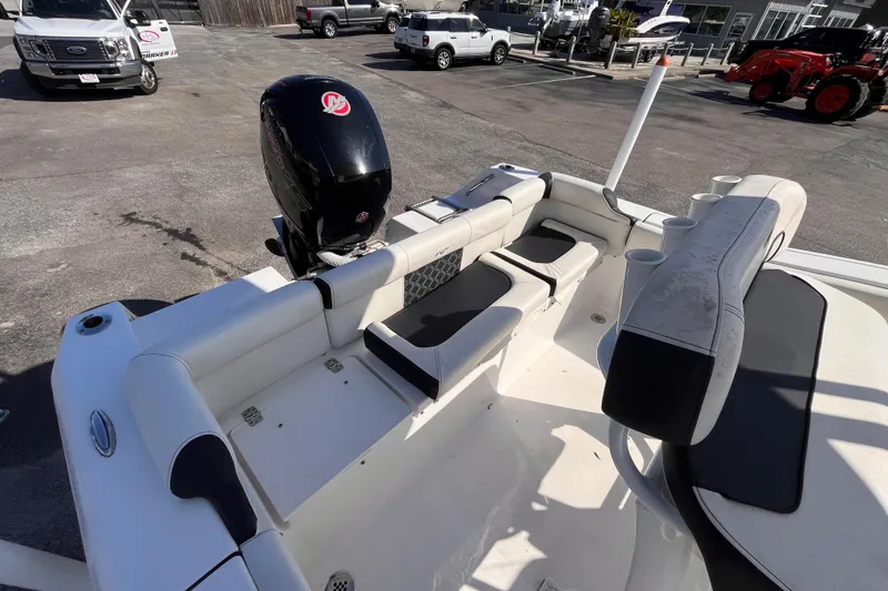 Slide: The Image of 2022 Tidewater 210 LXF boat interior with seating and outboard motor in a parking lot. - 5