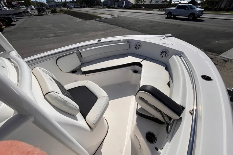 Slide: The Image of 2022 Tidewater 210 LXF boat interior with seating and speakers, parked near a road. - 9