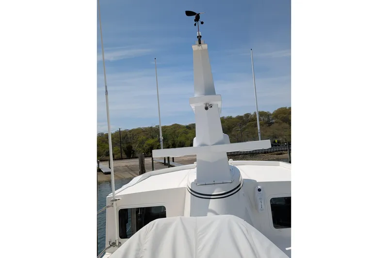 Slide: The Image of 2005 American Tug 41 boat deck with radar and antennas, docked near a wooded shoreline. - 19
