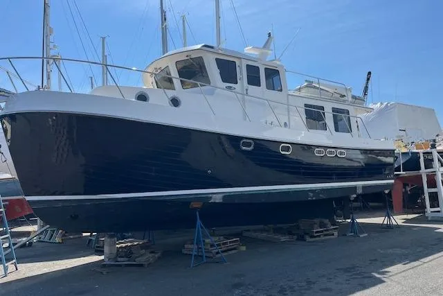 Slide: The Image of American Tug 41, 2005 model, docked on land for maintenance under clear blue sky. - 2