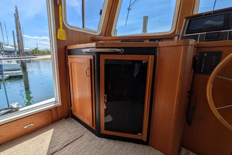 Slide: The Image of Interior of a 2005 American Tug 41, featuring wooden cabinetry and a window view of the marina. - 37