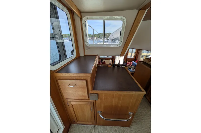 Slide: The Image of Interior of 2005 American Tug 41, featuring wooden cabinetry and window view of marina. - 46
