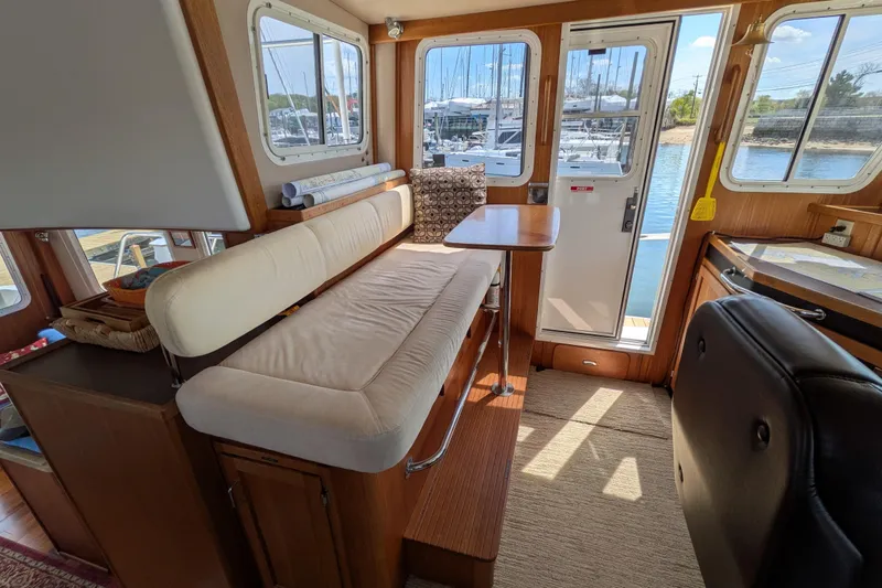 Slide: The Image of Interior of 2005 American Tug 41, featuring seating and table with marina view. - 49