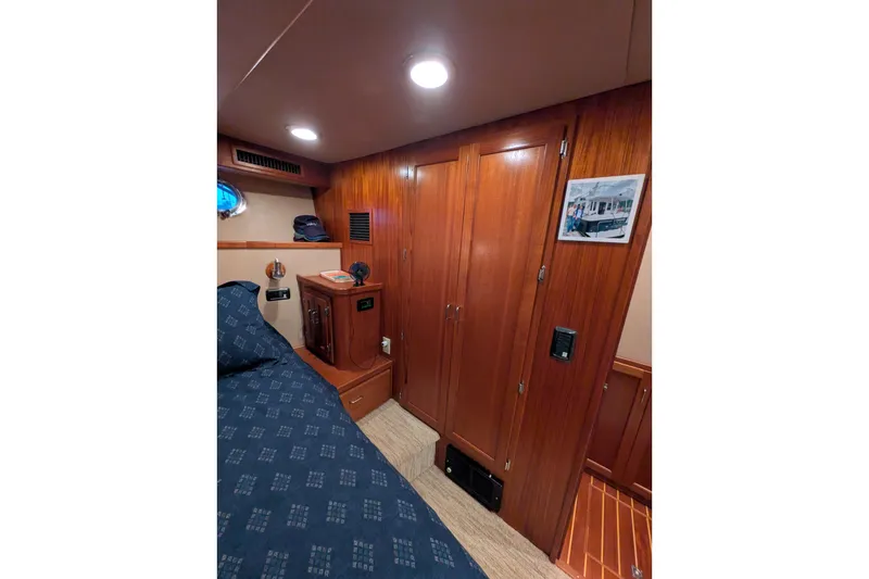 Slide: The Image of Cozy cabin interior of 2005 American Tug 41 with wooden cabinetry and blue bedding. - 58