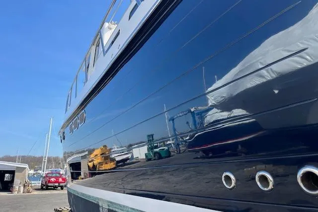 Slide: The Image of 2005 American Tug 41 yacht with sleek, reflective hull in a marina setting. - 7
